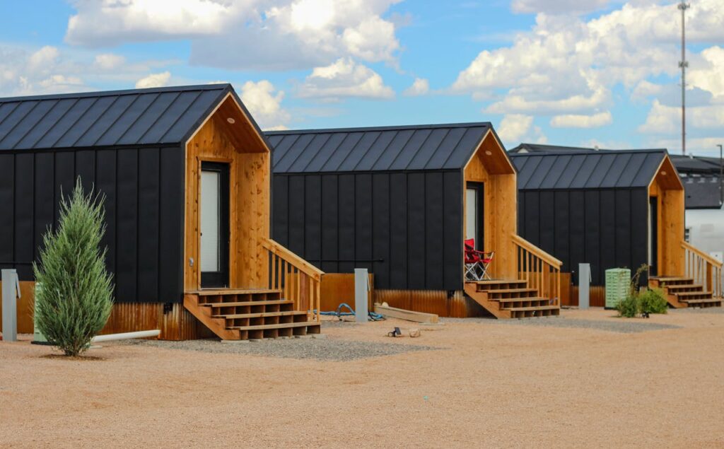 Row of modern black tiny houses in a desert setting under a cloudy sky.